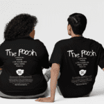Two individuals sitting side by side wearing black T-shirts with 'The Pooch' design on the back, listing major cities (London, Paris, Los Angeles, New York, Tokyo) and a cloud graphic with 'CC' initials.