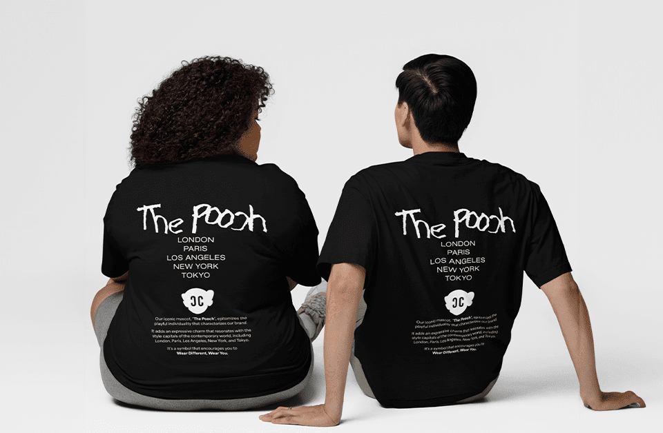 Two individuals sitting side by side wearing black T-shirts with 'The Pooch' design on the back, listing major cities (London, Paris, Los Angeles, New York, Tokyo) and a cloud graphic with 'CC' initials.